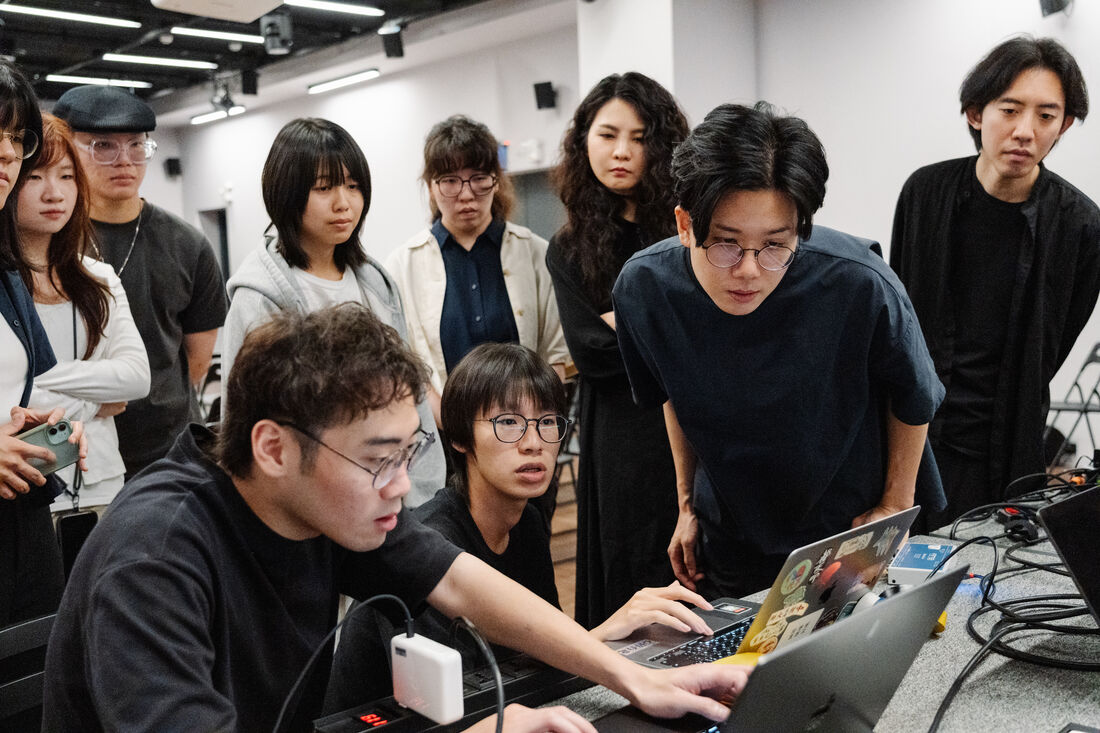 開演前技術檢查：學生操作筆電，旁邊圍著同組成員與桌上的訊號線